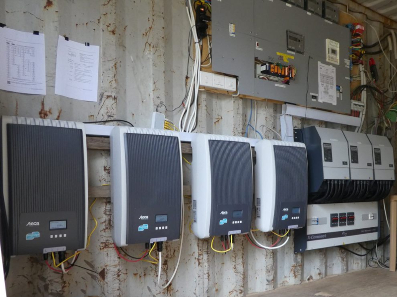 Vier Stecca-Wechselrichter und drei Studer Xtender sowie eine Elektrotafel im Container beim SILAP Guesthouse in Ghana, mit Einblick in die Verdrahtung.
