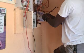 Ein Installateur bearbeitet Drähte am offenen Schaltschrank des örtlichen Stromlieferanten. Gut sichtbar ist eine gängige, aber gefährliche Verbindungstechnik der Ghanaer.