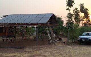 Die PV-Anlage in Bimbilla von vorne, daneben ein Pickup-Truck, ein gängiges Auto für Ghana, mit einem schönen Sonnenuntergang im Hintergrund.