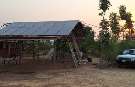 Die PV-Anlage in Bimbilla von vorne, daneben ein Pickup-Truck, ein gängiges Auto für Ghana, mit einem schönen Sonnenuntergang im Hintergrund.